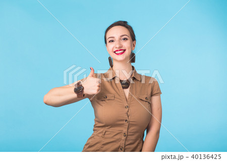 Cheerful young brunette caucasian student girl showing thumbs up on blue background with copy space 40136425