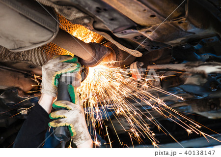 repairer cuts old silencer on car by angle grinder 40138147