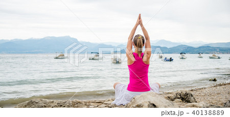 Woman meditating at the lake Woman meditating at the lake 40138889