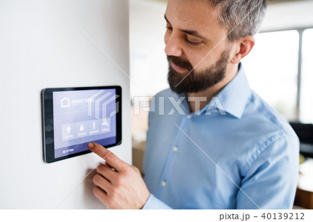 A man pointing to a tablet with smart home screen at home. 40139212