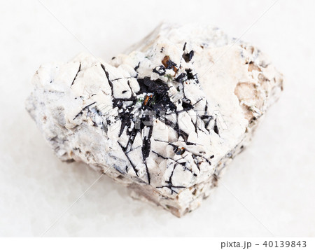 Ilmenite black crystals on raw stone on white Ilmenite black crystals on raw stone on white 40139843