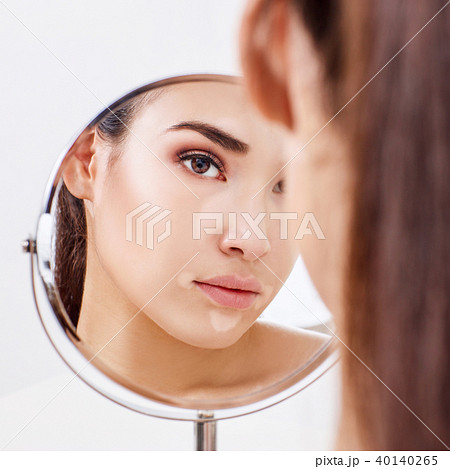 Beautiful woman with vitiligo looking in the mirror. Beautiful woman with vitiligo looking in the mirror. 40140265