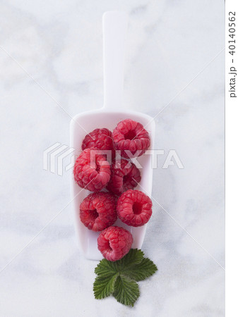 White scoop with fresh raw organic raspberries White scoop with fresh raw organic raspberries 40140562