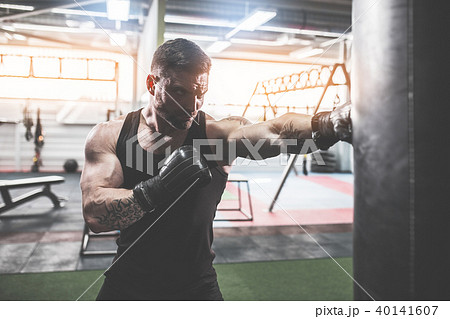 Male boxer training with punching bag in dark sports hall. 40141607