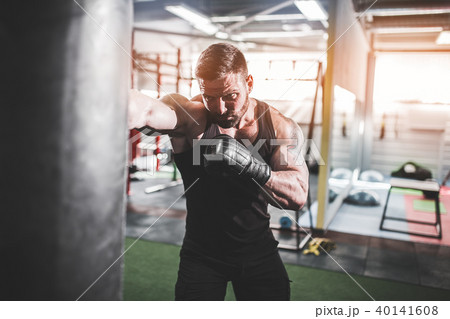 Male boxer training with punching bag in dark sports hall. 40141608