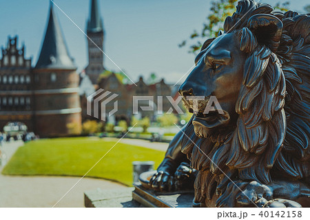 Bronze Lion statue in front of Holsten Gate - Holstentor, a city gate marking off the western Bronze Lion statue in front of Holsten Gate - Holstentor, a city gate marking off the western 40142158