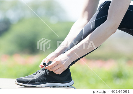 スニーカーの靴紐を結ぶ女性の足下 40144091