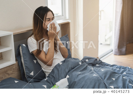 Asian woman feeling unwell and sneezing Asian woman feeling unwell and sneezing 40145273