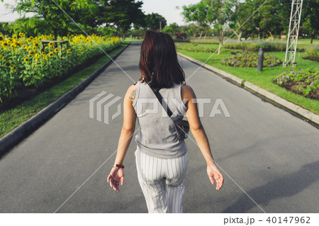 Back side of young woman walking in the park Back side of young woman walking in the park 40147962