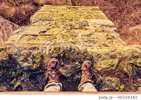 Tourist standing on high stone wall, yellow filter 40149382