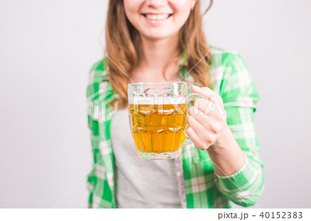 Closeup of young woman holding a beer mug full of beer and smiling on white background Closeup of young woman holding a beer mug full of beer and smiling on white background 40152383