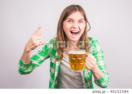 Cheerful young woman holding a beer mug full of beer and smiling on white background Cheerful young woman holding a beer mug full of beer and smiling on white background 40152384