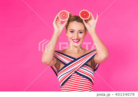 Smiling girl with grapefruit cut in half fruit in hand on pink background 40154079