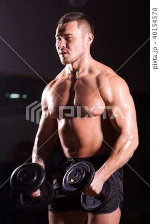 Handsome power athletic man with dumbbell. Strong bodybuilder with six pack, perfect abs, shoulders 40154578