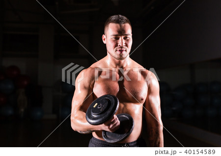 Handsome power athletic man with dumbbell. Strong bodybuilder with six pack, perfect abs, shoulders 40154589