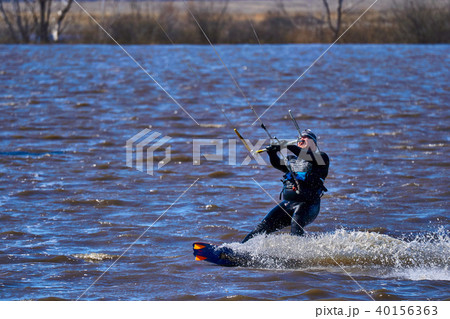 Male kiteboarder rides on a board along the river 40156363