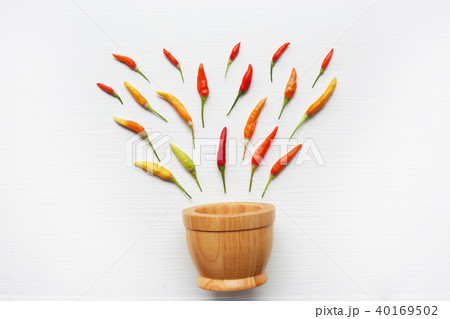 Colorful chili peppers with wooden mortar on white Colorful chili peppers with wooden mortar on white 40169502