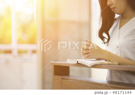 Woman praying on a holy bible in church 40171144