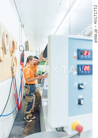 Two carpenters cleaning veneer machine in workshop Two carpenters cleaning veneer machine in workshop 40171752