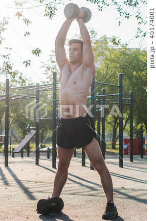 Muscular male athlete with arms raised doing lifting exercises dumbbells. Muscular male athlete with arms raised doing lifting exercises dumbbells. 40174001