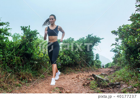 Fitness female athlete running on forest path in mountainous area in summer. Sporty woman working 40177237