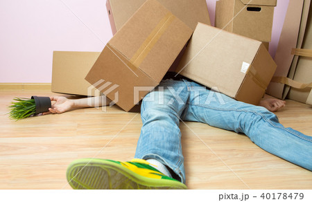 Image of man in jeans lying under cardboard boxes 40178479