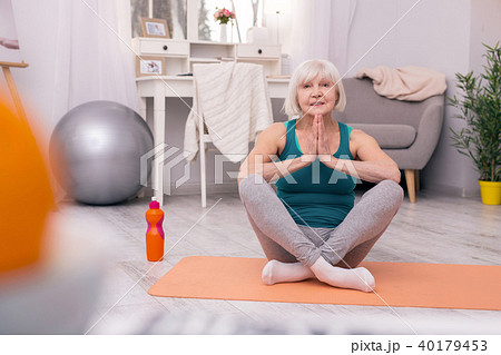 Charming elderly woman meditating at home Charming elderly woman meditating at home 40179453