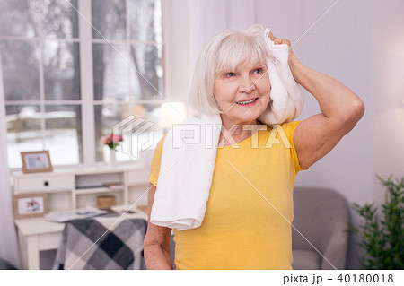 Charming elderly woman towel-drying her hair after workout 40180018