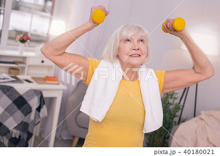 Cheerful senior woman lifting up dumbbells 40180021