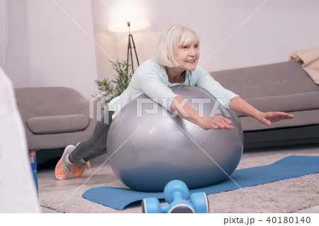 Pleasant elderly woman lying on exercise ball Pleasant elderly woman lying on exercise ball 40180140