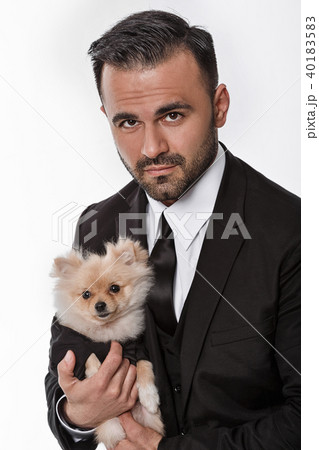 man in black suit holds pomeranian dog man in black suit holds pomeranian dog 40183583