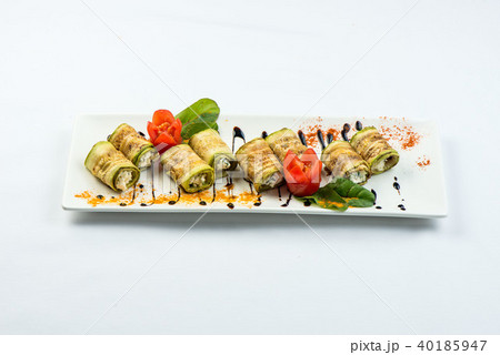 Grilled zucchini roll with a stuffing on a white plate on a white background Grilled zucchini roll with a stuffing on a white plate on a white background 40185947