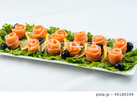 salmon snack on lettuce leaf with lemon and olives on white plate on white background salmon snack on lettuce leaf with lemon and olives on white plate on white background 40186399