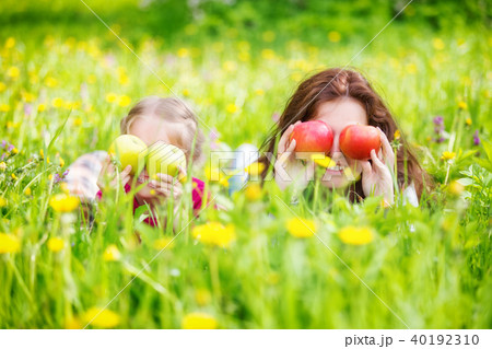 Mother and daughter on sunny meadow with apples in hands Mother and daughter on sunny meadow with apples in hands 40192310