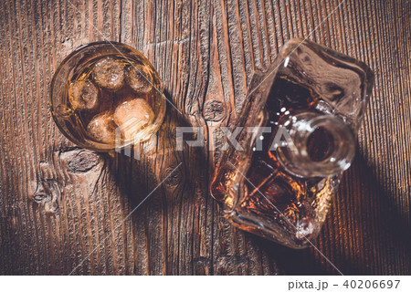 Glass of whiskey with ice cubes and whiskey bottle 40206697