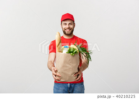 Delivery Concept - Handsome Cacasian delivery man carrying package bag of grocery food and drink 40210225