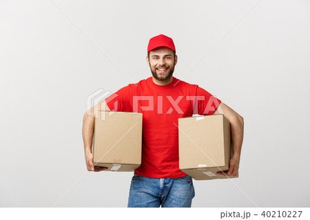 Delivery Concept: Smiling handsome caucasian delivery man holding a paper box. Isolated over grey 40210227