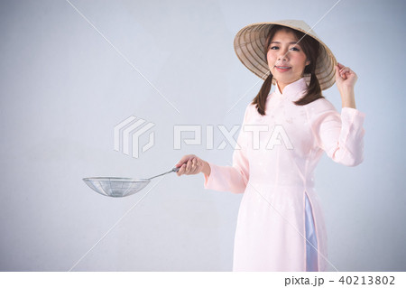 woman in pink dress and vietnam hat holding cookin 40213802