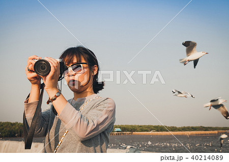 Asian woman talking picture of seascape and birds. 40214089