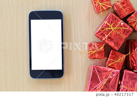 Empty Screen of Smartphone and red gift box are placed on a brown wooden floor. Empty Screen of Smartphone and red gift box are placed on a brown wooden floor. 40217317
