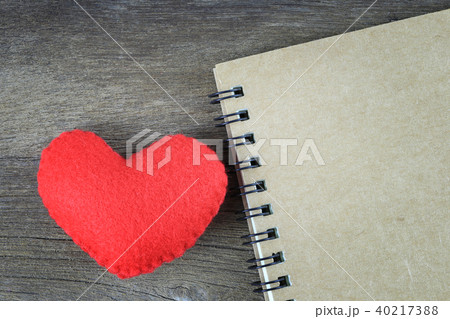 Red heart and blank brown notebook placed on a wooden floor. Red heart and blank brown notebook placed on a wooden floor. 40217388
