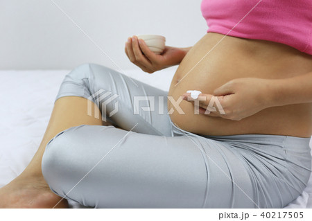 Pregnant mom is applying skin cream on the stomach. 40217505