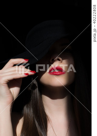 Girl with a finger at the mouth. A symbol of silence. The ray of the sun lights the girl in the dark 40222808
