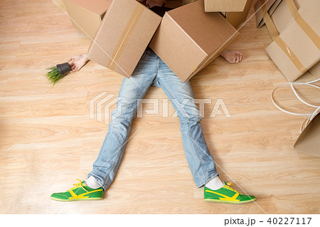 Photo of man in jeans and sneakers lying under cardboard boxes Photo of man in jeans and sneakers lying under cardboard boxes 40227117