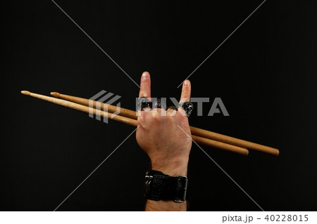 Man hand with drumsticks and devil horns on black 40228015