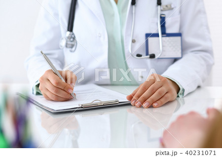 Female doctor filling up an application form while consulting patient. Just hands. Medicine an Female doctor filling up an application form while consulting patient. Just hands. Medicine an 40231071