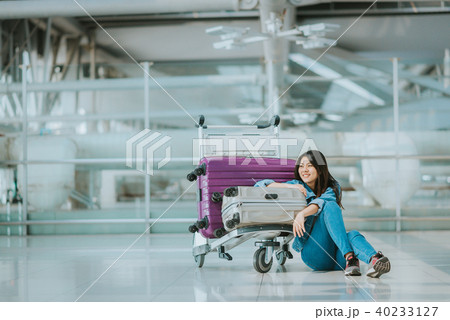 Asian woman passenger sitting with luggage trolley 40233127
