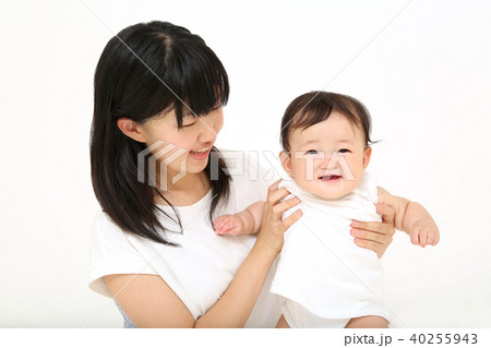 若いお母さんと遊ぶ笑顔の女の子の赤ちゃんの写真素材