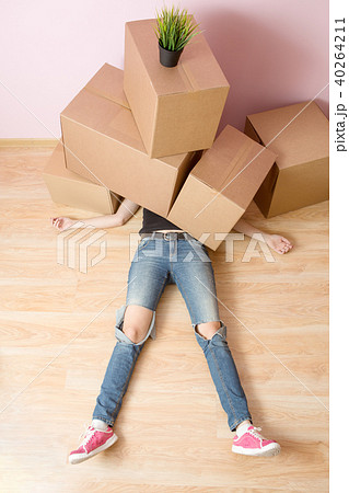 Photo of woman in jeans lying under cardboard boxes Photo of woman in jeans lying under cardboard boxes 40264211