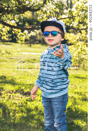 Child blond 3-4 years in blue with hat and sunglasess running around the Park 40268252